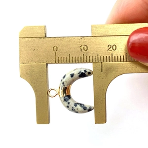 Macro shot measuring the 15mm crescent moon natural stone pendant with brass calipers