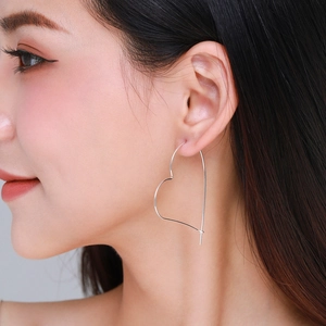Elegant silver hollow heart drop earrings worn by a model in a minimalist stylish look