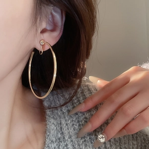 Model wearing large polished gold hoop earring in a minimalist and chic fashion style