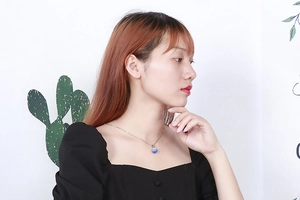 Detail view of a silver necklace with a sparkling blue crystal ball pendant on a model