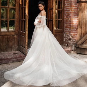 Elegante abito da sposa bianco con spalle scoperte, maniche in tulle e strascico