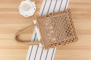 Flat lay of a beige cotton rope woven tote bag on a wooden table with vacation vibes