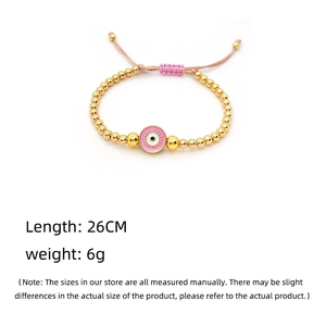 Detail of pink evil eye charm on adjustable gold beaded handmade woven bracelet