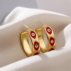 Detailed macro view of gold-plated hoop earrings with red and white evil eye enamel patterns