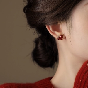Boucles d'oreilles dragon en émail rouge portées par un mannequin en pull rouge