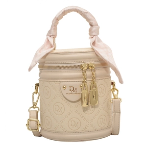 Beige cylindrical bucket bag with monogram embossing and silk scarf handle detail