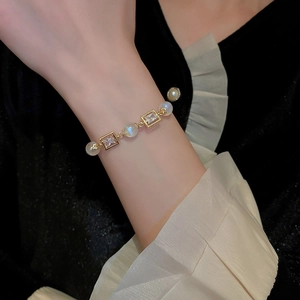 Detailed view of adjustable golden bracelet with square zircon and mermaid pearls