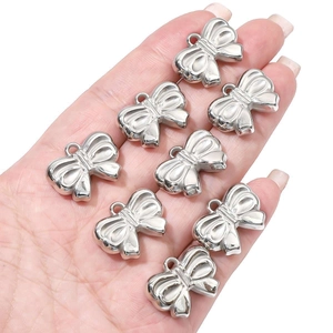 Detailed view of silver bow-knot charms held in hand for size and texture reference