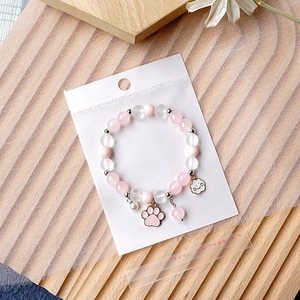 Pink and white beaded bracelet with cat paw charm in self-sealing OPP jewelry bag