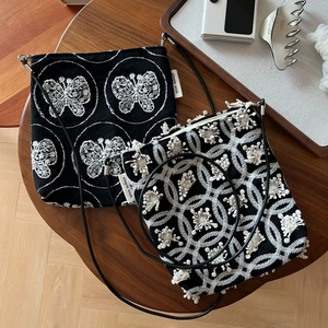 Detail view of two black canvas bags with white butterfly and floral embroidery on a table