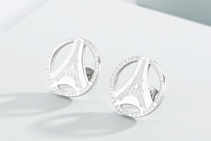 Macro detail of silver stainless steel round earring with Eiffel Tower cutout and engraving