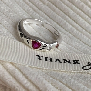 Detailed close-up of a 925 silver ring featuring red heart gems and wing engravings