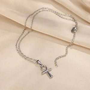 Detail of silver Ankh cross pendant with fine metal chain and lobster clasp on beige fabric