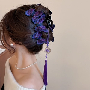 Dettaglio molletta per capelli a farfalla ricamata con nappa viola su una modella