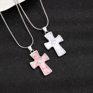Close-up of pink and white marble texture cross pendants with silver frames and chains