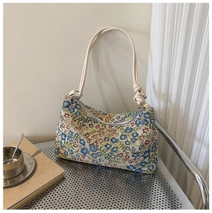 Detailed texture of woven floral underarm bag with blue and red patterns and rope strap