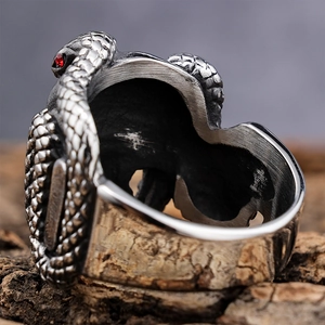 Vintage punk cobra skull ring in stainless steel with red gemstone on aged wood surface