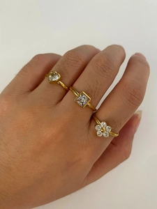 Détail de trois bagues en titane plaqué or avec zircons en forme de cœur, carré et fleur