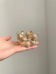 Close-up of golden floral bracelet with mesh textures and sparkling crystal centerpieces