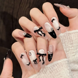 Gros plan d'ongles œil de chat avec nœuds noirs 3D, pointes françaises et strass argentés