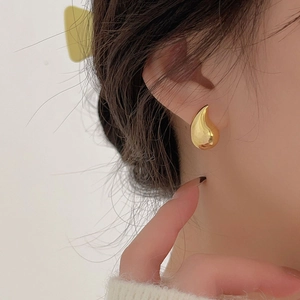 Close-up of elegant gold teardrop earrings showing high-polished metallic reflection