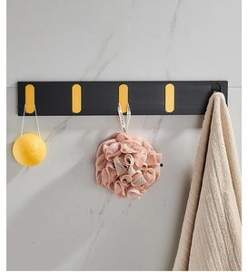 Detail of wall-mounted black and gold folding hooks with five adjustable aluminum hangers