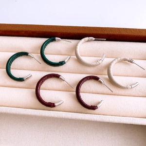 Détail de créoles en forme de C en similicuir crocodile vert, beige et bordeaux