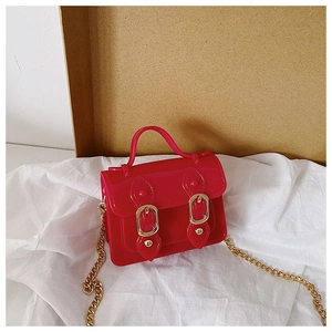 Detail of red jelly crossbody bag with gold chain strap and decorative buckles