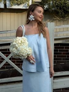 Detail of light blue cotton linen camisole and maxi skirt set with white floral earrings