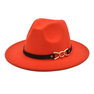 Dettaglio del cappello fedora arancione con fascia in pelle nera e fibbia a catena d'oro