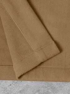 Detailansicht der Strickbündchen und feinen Nähte an einer kamelbraunen Wolljacke