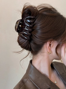 Close-up of large brown acrylic claw clip holding thick hair in a stylish updo hairstyle