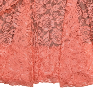Détail du tissu en dentelle florale rose saumon avec texture en maille et motifs