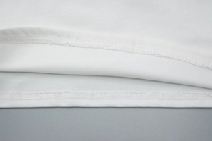 Detailed macro view of the double-needle stitching and lace trim on a white camisole hem