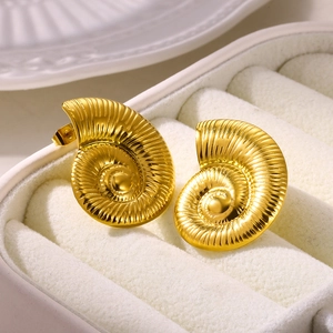 Macro detail of golden seashell-shaped stainless steel earrings in a white gift box