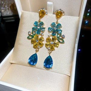 Detail of flower tassel earrings with blue teardrop crystals in a beige velvet gift box