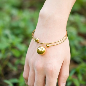 Gold-plated stainless steel double-bead bangle with round pendant worn on a wrist