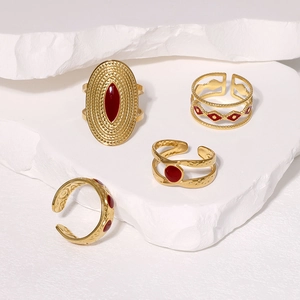 Close-up of four vintage gold rings with red enamel set on white stone pedestals