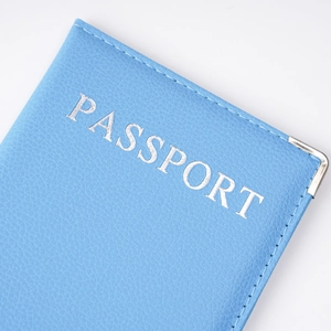 Macro shot of blue PU leather passport cover with silver lettering and metal corner