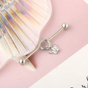 Detailed macro view of silver industrial barbell earring with crystal butterfly pendant