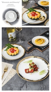 Close-up of luxury ceramic plates with gold rims and artistic feather patterns on stone table