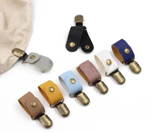 Nahaufnahme von bunten Hutclips aus Leder mit Narbung und Vintage Bronze Metallschnallen