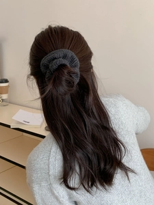 Détail de l'élastique à cheveux en tricot gris foncé porté par un modèle en chignon