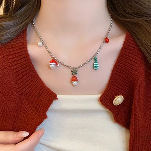 Close-up of Christmas tree and bell charms on a silver ball chain worn on a red sweater