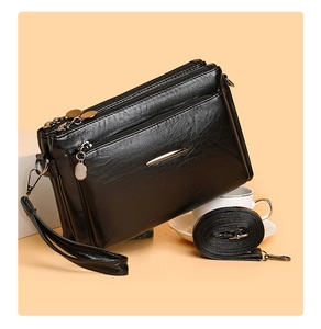Detail view of black PU leather handbag featuring multiple zipper compartments and metal accents