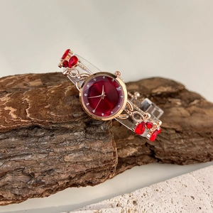 Detailed view of rose gold women's watch with red dial on natural stone backdrop