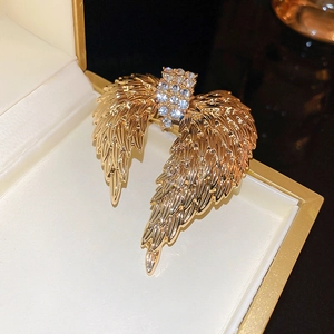 Macro shot of a luxury gold angel wing brooch with sparkling rhinestones in a gift box