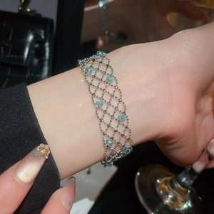 Detailed macro view of silver mesh bracelet with light blue crystal beads on wrist