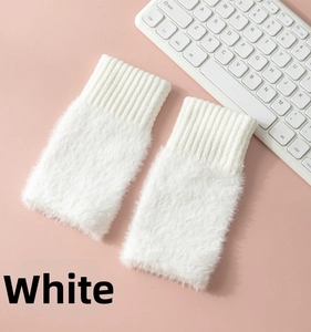 Close-up of white plush wrist warmers with knitted cuffs on a desk with keyboard