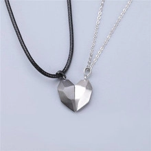 Detail of couple magnetic heart pendants with geometric facets and black braided leather cord